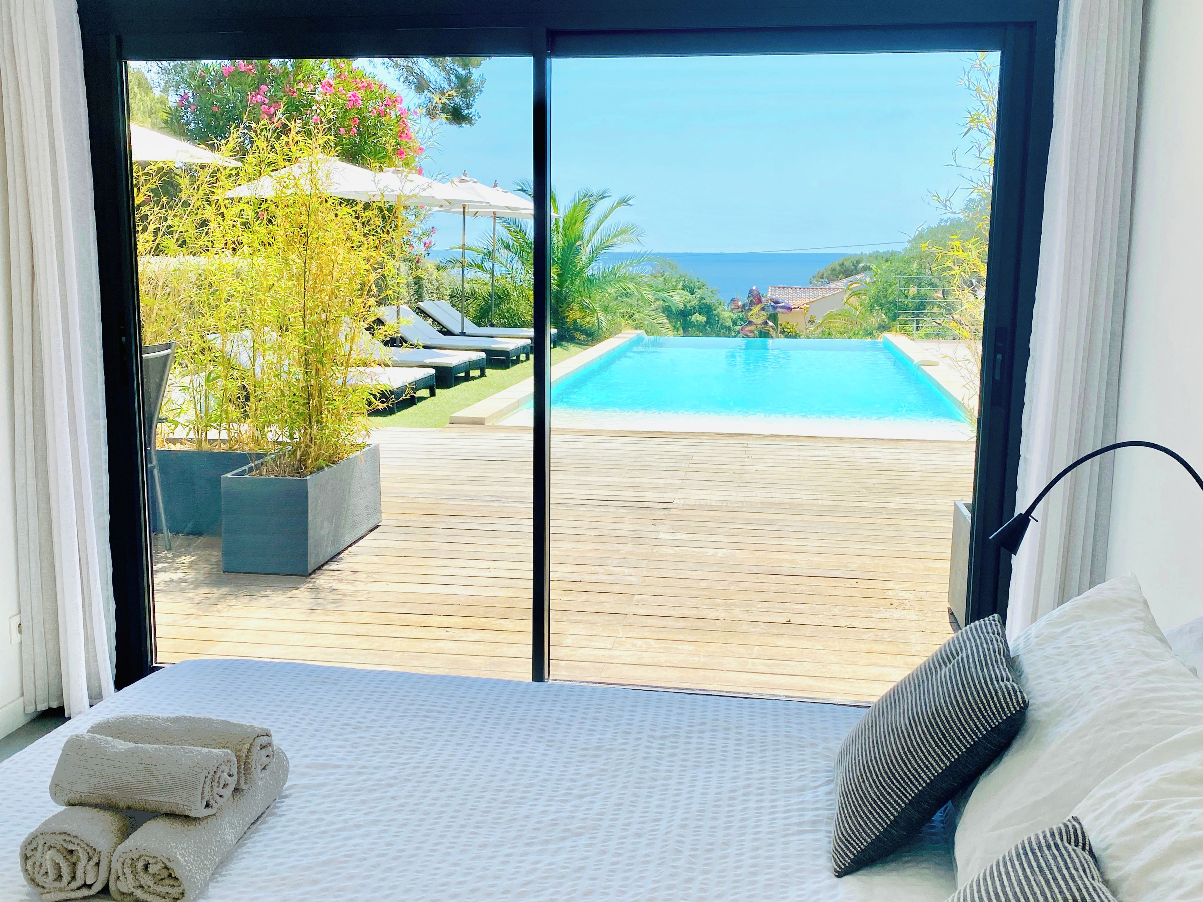 Ein Schlafzimmer mit Blick auf einen Swimmingpool, ein Bett mit Handtüchern und ein Blumentopf.
