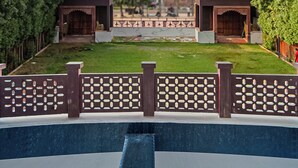 A courtyard with a pool, surrounded by a decorative fence and trees. - The Heritage Bagh (Luni)