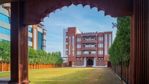 A courtyard with a traditional building featuring arched windows and a central entrance. - The Heritage Bagh (Luni)
