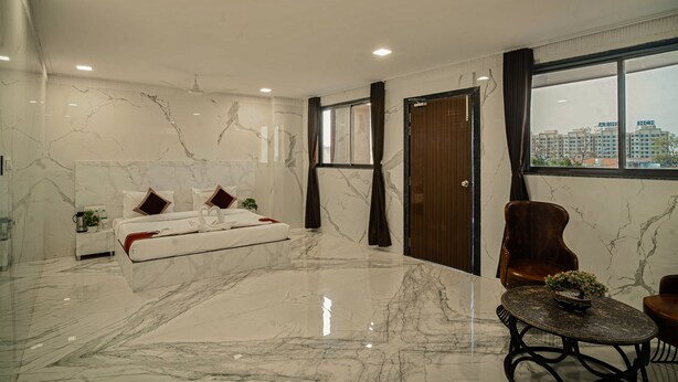 A modern bedroom with a large bed, a sitting area, and a view of the city. - The Heritage Bagh (Luni)