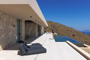 Ein moderner Poolbereich im Freien mit Steinwänden und freiem Blick auf das Meer.