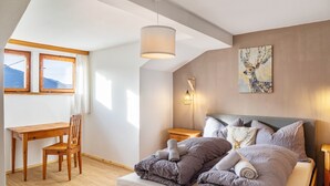 Een slaapkamer met een bed, een bureau, een stoel, een lamp en een schilderij aan de muur.