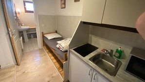 Une petite cuisine équipée comprenant un lit, un évier et un four à micro-ondes.