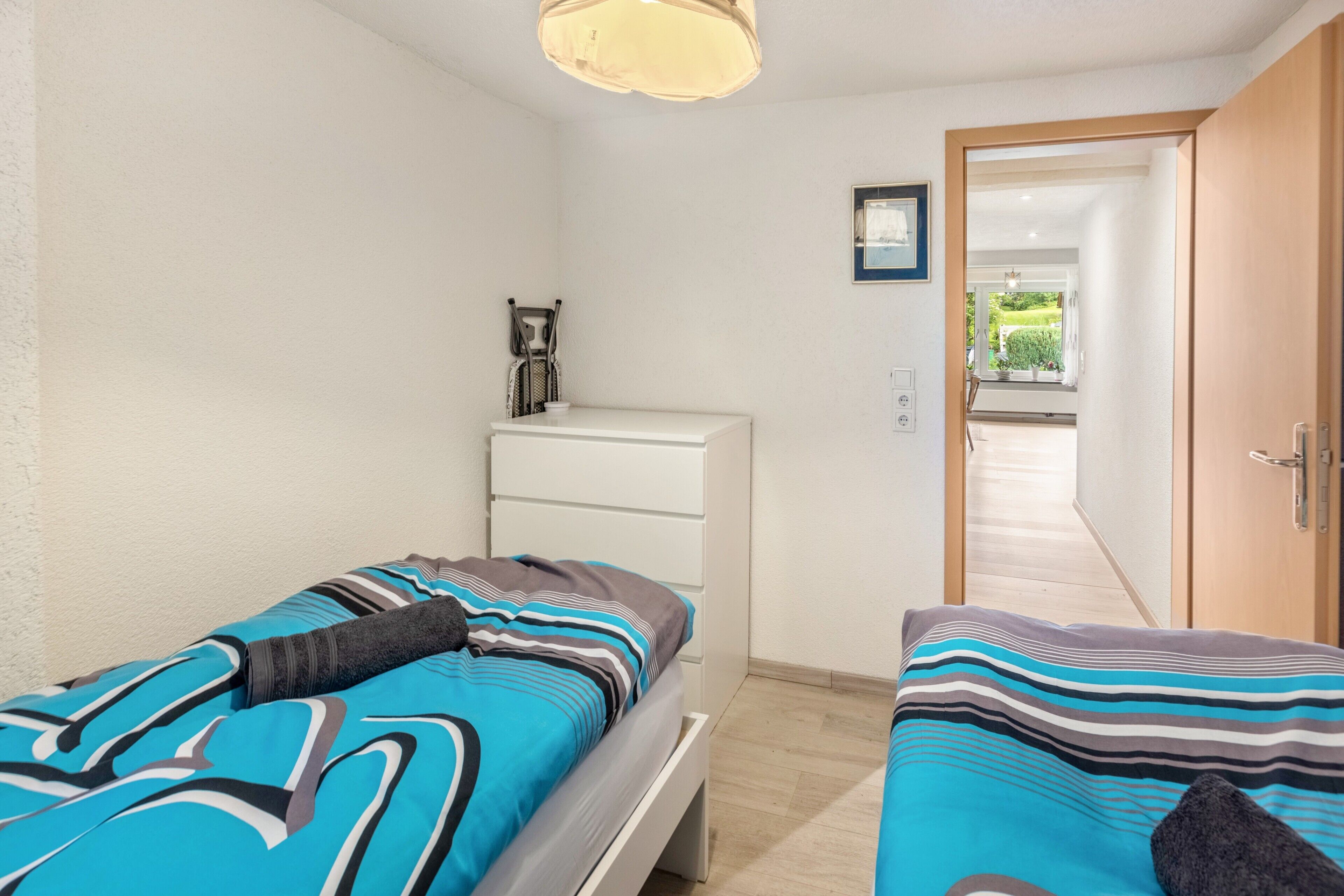 Une chambre avec deux lits, un bureau et une porte donnant sur un couloir.