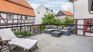 Een balkon met een zithoek, een lounge stoel en een plant in pot.