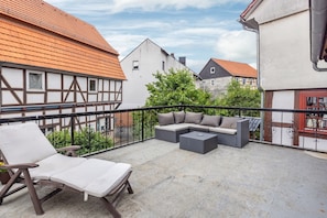 Een balkon met een zithoek, een lounge stoel en een plant in pot.