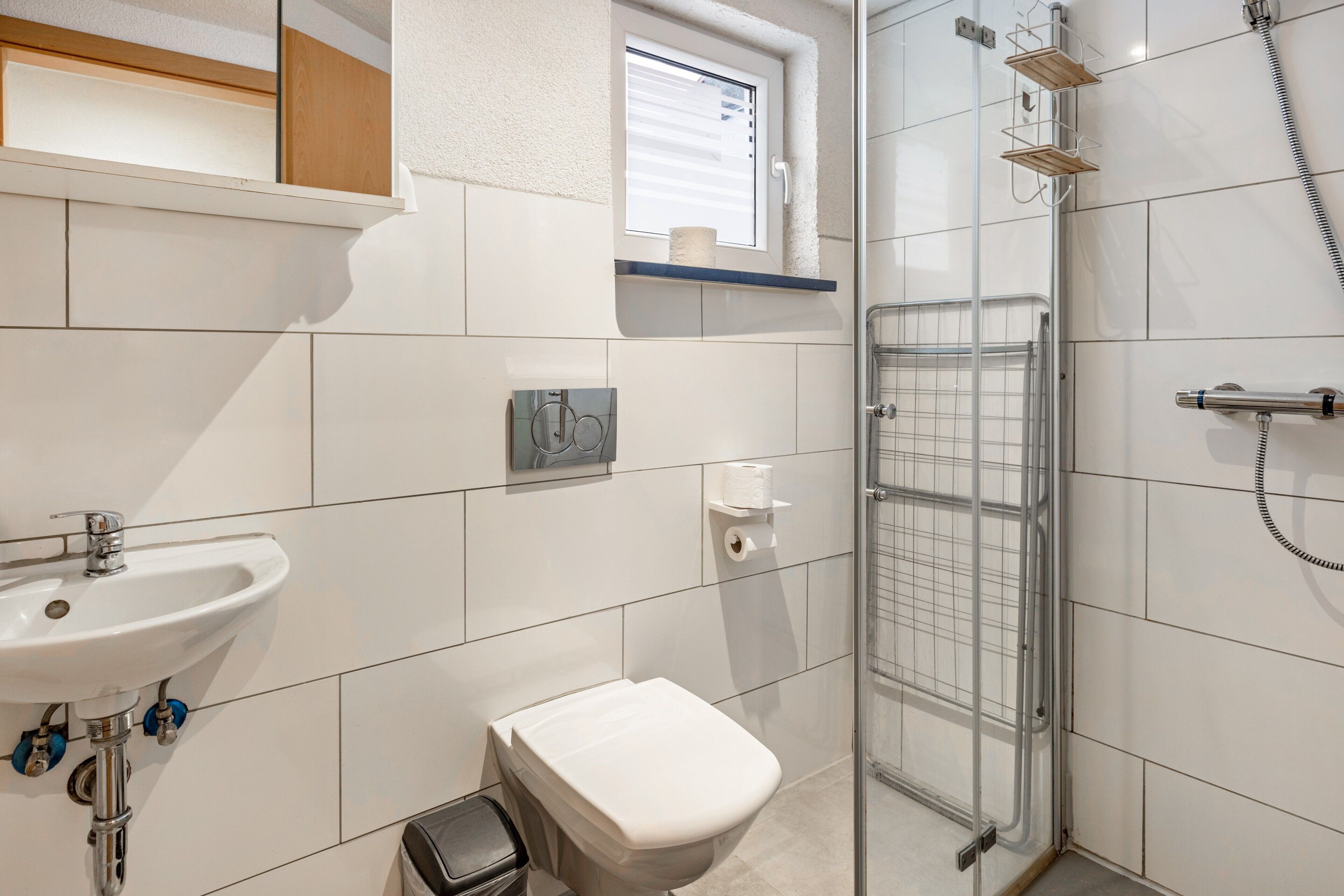 Ein Badezimmer mit Waschbecken, Toilette, Dusche und einem Fenster.