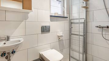 Ein Badezimmer mit Waschbecken, Toilette, Dusche und einem Fenster.