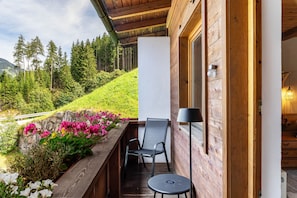 Een houten balkon met een stoel, een tafeltje en een lamp.