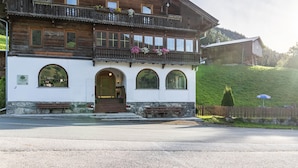 A traditional wooden building with balconies, arched windows, and a stone foundation. - Double Room 'Zirben Nest' with Stunning View and Private Floor Bathroom (Hainzenberg)