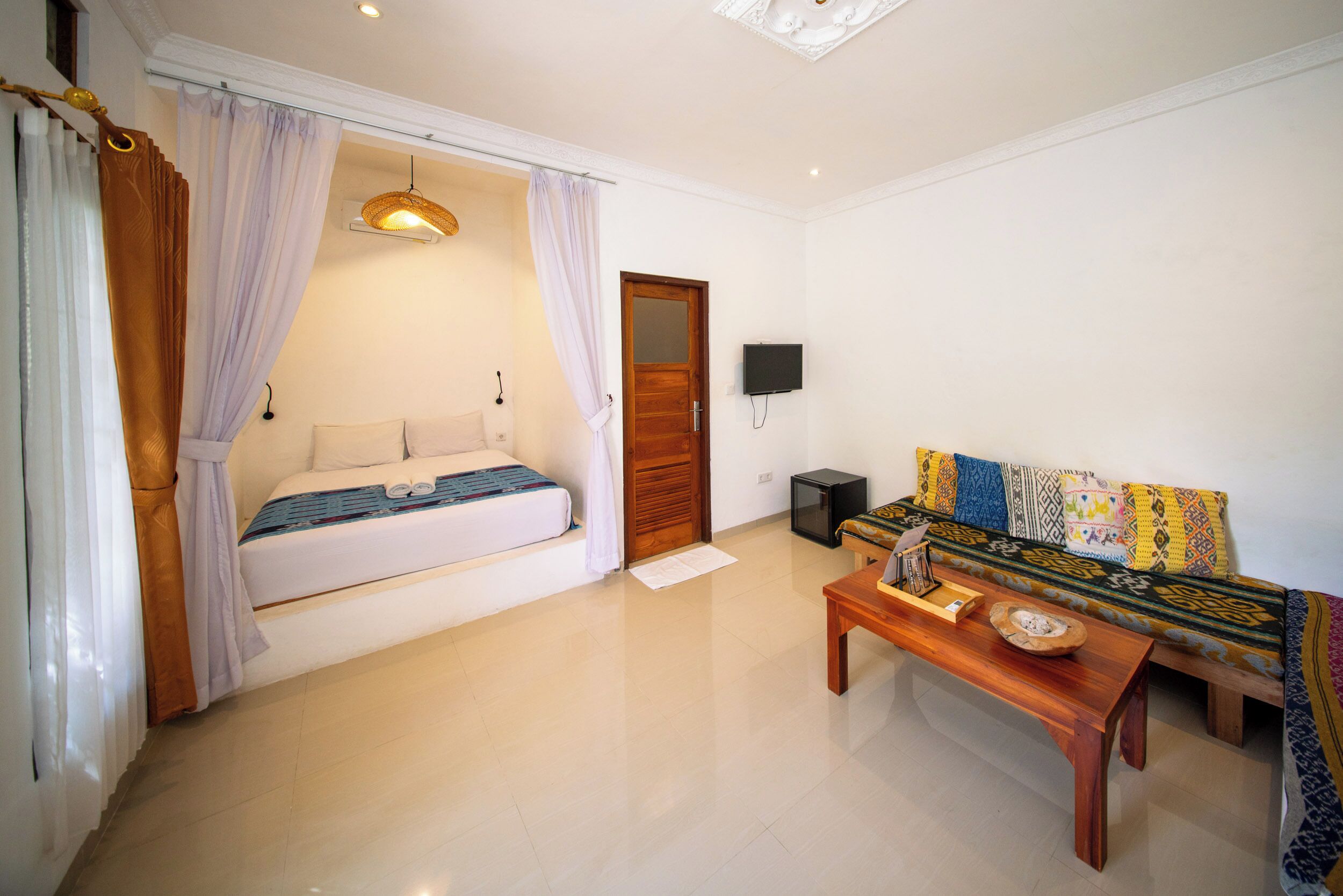 A room with a bed, a wooden sofa, a TV, and a small table.