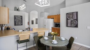 A modern kitchen with a central island, bar stools, and a dining table with chairs. - 5BR,3BA Villa in Solana Resort,Pool,Near Disney (Davenport)