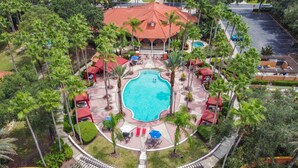 An aerial view of a resort with a central swimming pool, surrounded by palm trees and covered seating areas. - 5BR,3BA Villa in Solana Resort,Pool,Near Disney (Davenport)