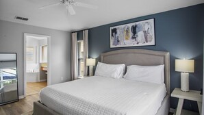 A bedroom with a large bed, a ceiling fan, a painting on the wall, and a view of the bathroom. - 5BR,3BA Villa in Solana Resort,Pool,Near Disney (Davenport)
