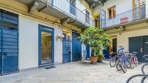 Un cortile con una pianta in vaso, biciclette e un edificio con porte e balconi blu.