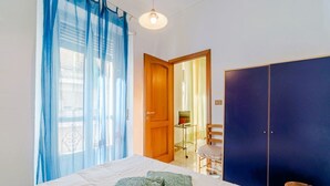 Una camera da letto con un letto, un armadio, una sedia e una scrivania con un computer.