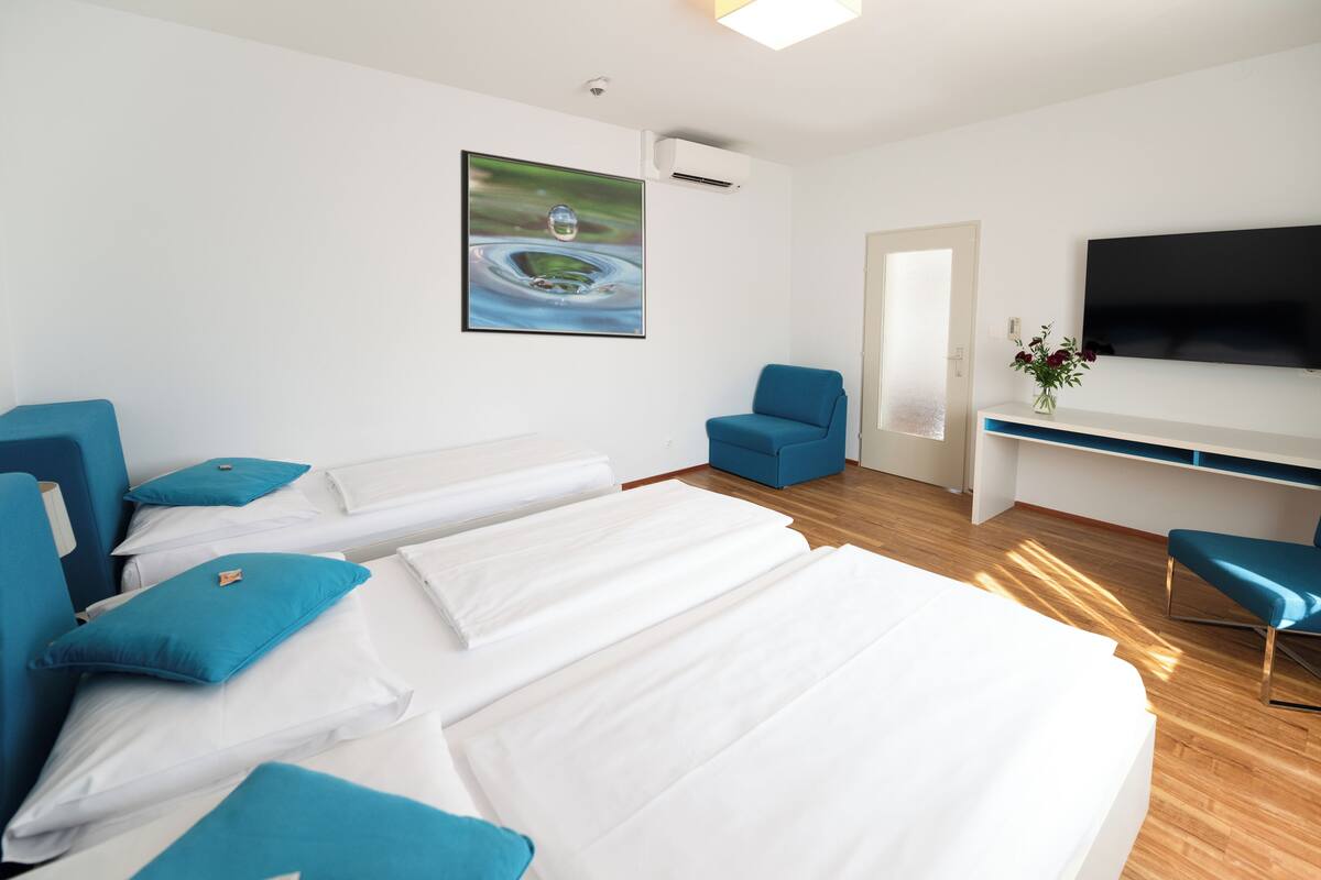 A hotel room with two beds, a TV, a desk, and a chair.