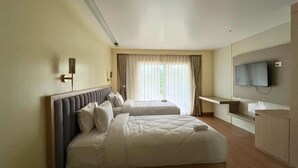 A hotel room with two beds, a flat-screen TV, a desk, and a window with curtains. - Hatimurias Boutique Resort (Sonapur)