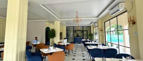 A restaurant with a checkered floor, blue and orange chairs, and a chandelier.