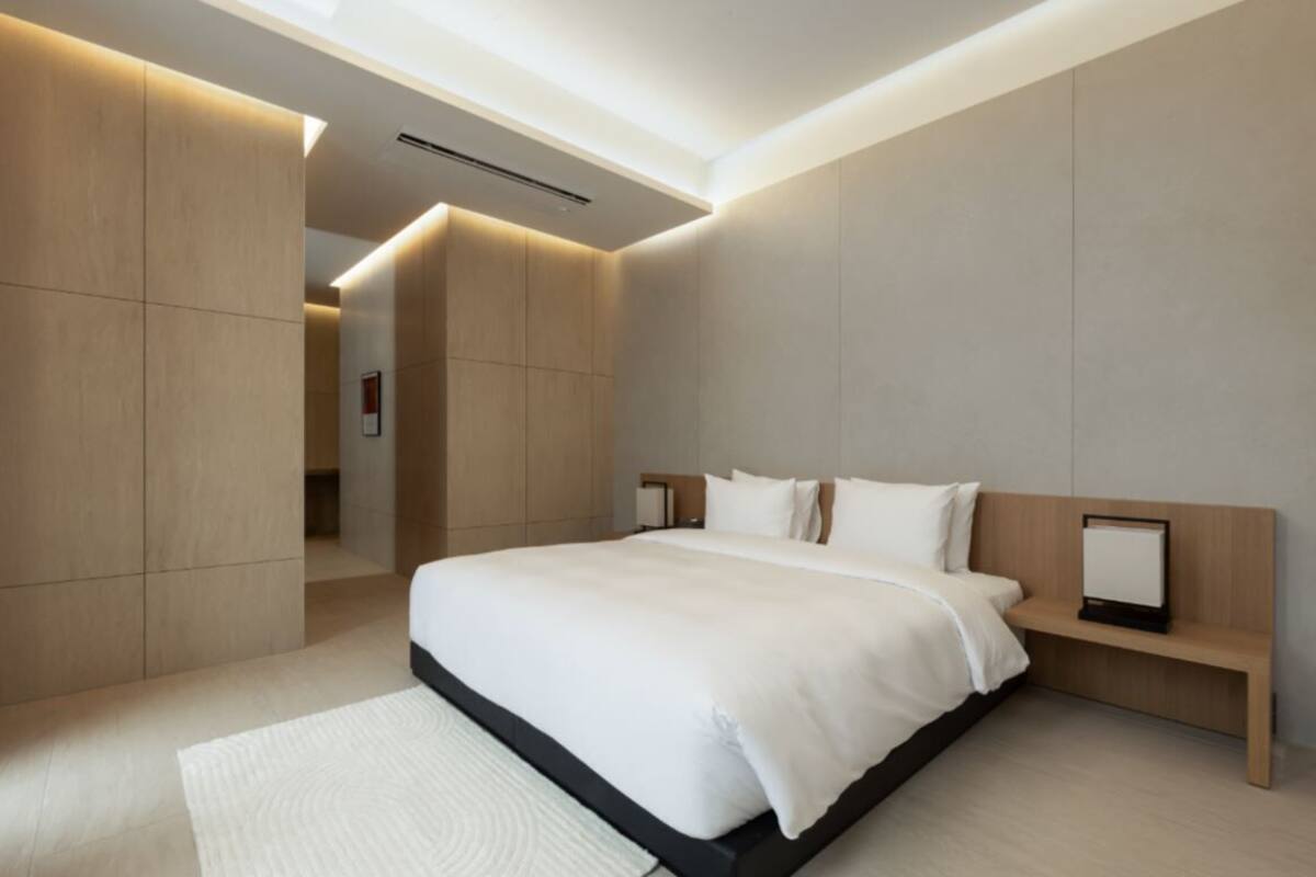 A modern bedroom with a large bed, built-in shelving, and a skylight.