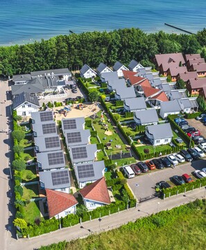 Ett bostadsområde med hus, solpaneler och en strand.