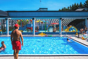A swimming pool with a covered area, slides, and play structures. - Collins Beach (Sianożęty)