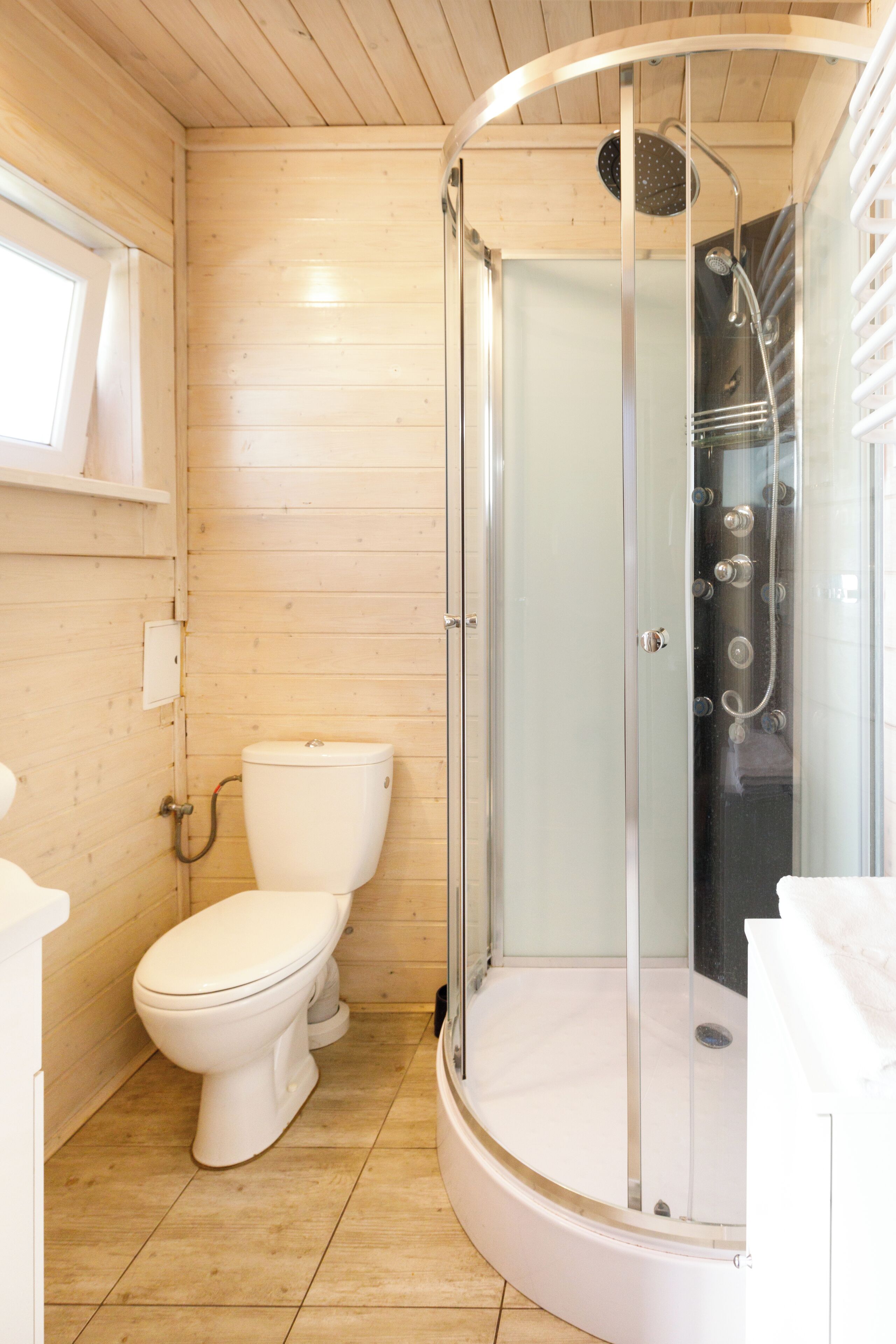A wooden interior bathroom with a glass-enclosed shower, a toilet, and a sink.