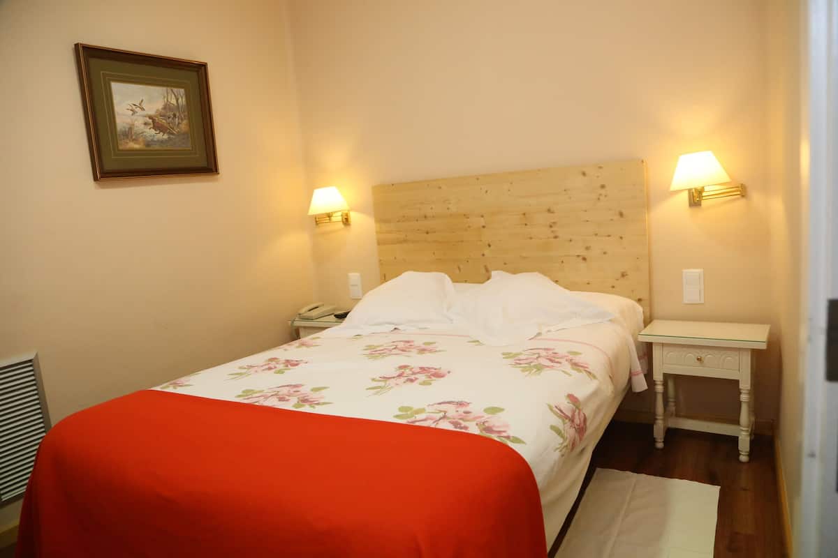 A bedroom with a wooden headboard, two bedside lamps, a telephone, and a floral bedspread.