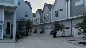 Une rangée de maisons de ville modernes, dotées de garages attenants, d’allées pavées et de petits arbres.
