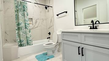 A modern bathroom with a bathtub, toilet, and sink.