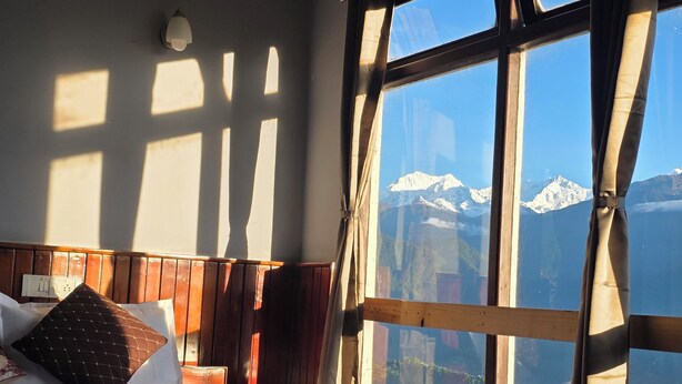Un dormitorio con un ventanal grande que da a una cadena montañosa.
