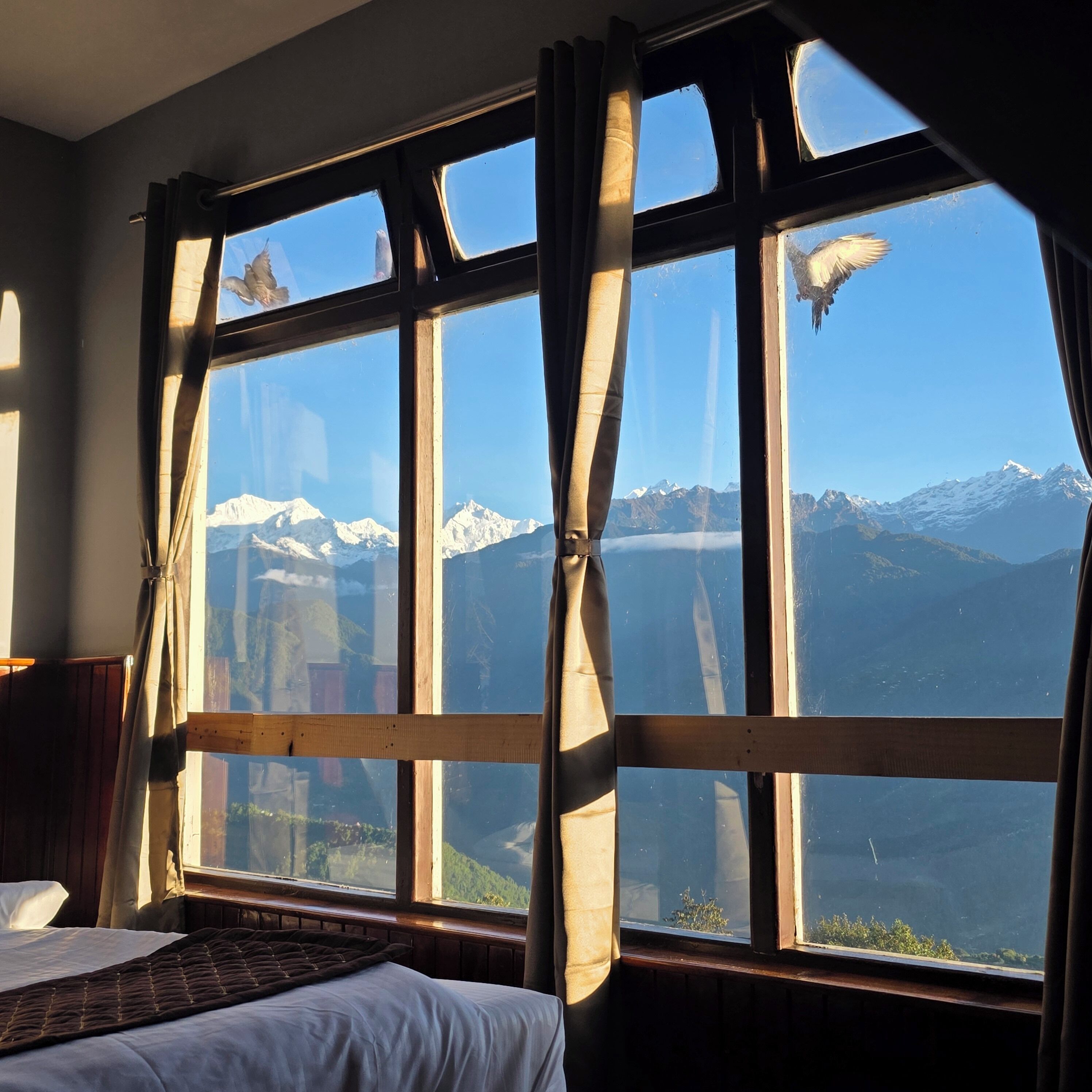 A room with a large window overlooking snow-capped mountains.