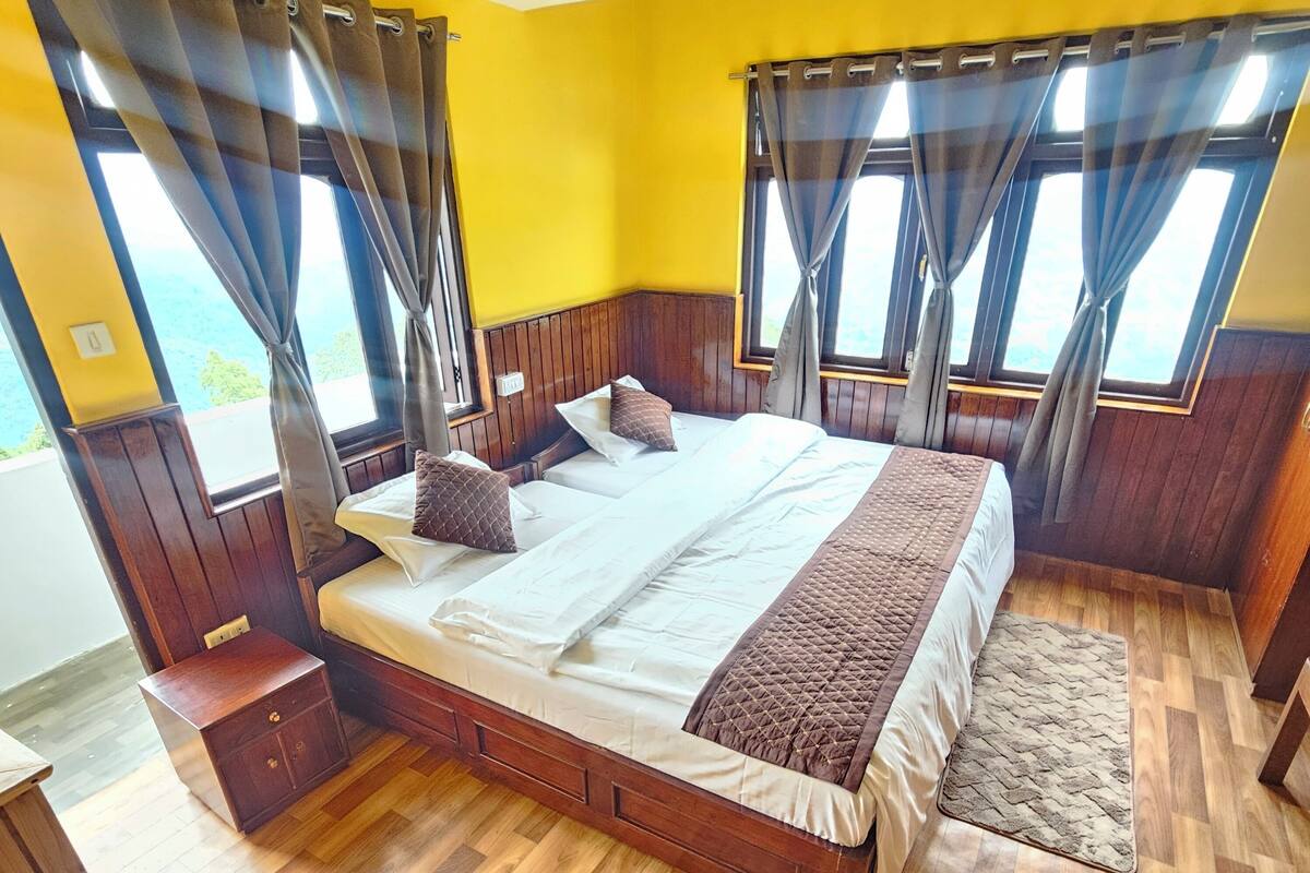 A double bed with a wooden headboard and footboard, two pillows, and a brown throw blanket.