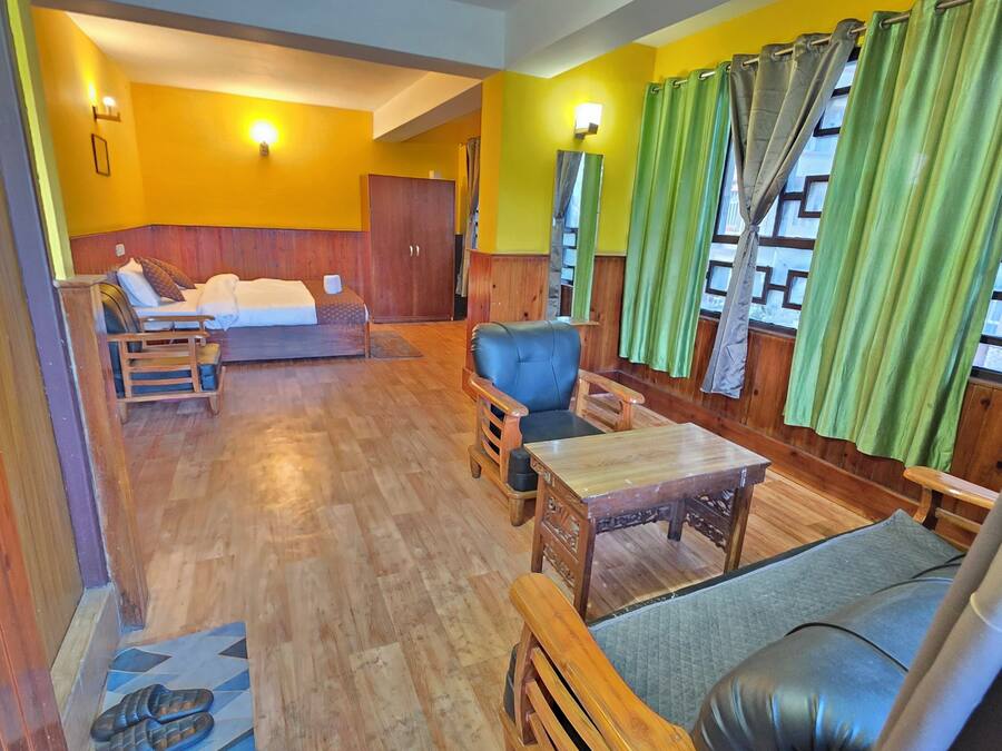 Una habitación con una cama, dos sofás, una mesa de madera y un espejo.