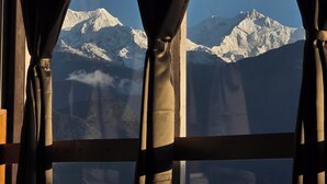 Una ventana con cortinas enmarca una vista de montañas nevadas.