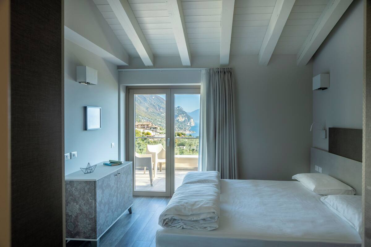 A hotel room with a bed, a desk, a chair, and a view of mountains.