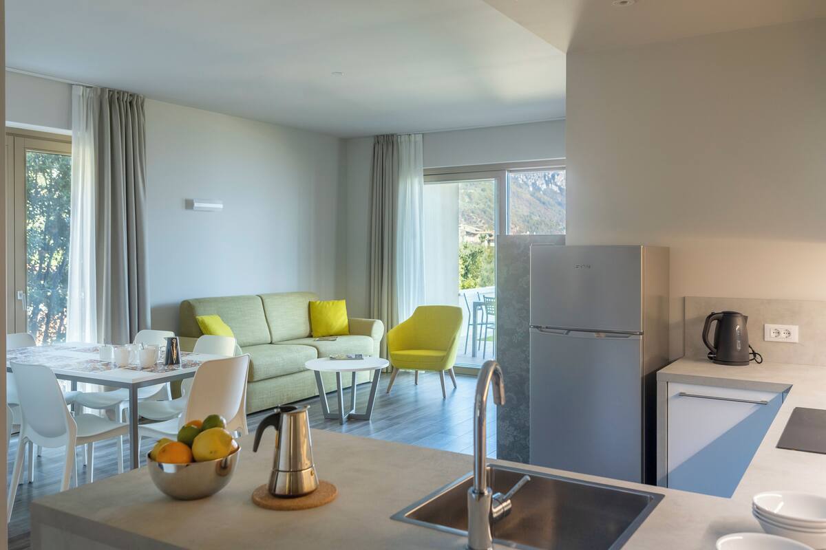A modern kitchen with a sink, a refrigerator, and a dining area with a table and chairs.