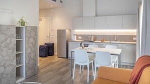 A modern kitchen with a dining area, a sofa, and a laptop on a table. - Relais Zenner (Toscolano Maderno)