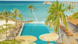 A pool with a wooden deck, palm trees, and a view of the ocean. - Meyyafushi Maldives - Premium All Inclusive (Meyyafushi)