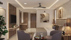 Un dormitorio moderno con cama, dos sillones, televisor y ventilador de techo.
