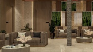 Un vestíbulo moderno con sofás, una mesita de centro y plantas decorativas.