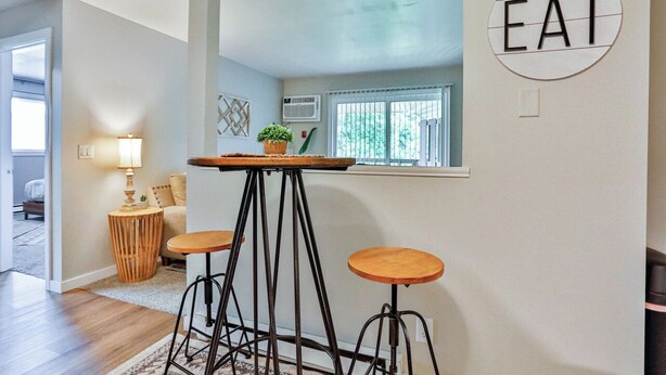 A modern kitchen with a central island, stools, and a 'EAT' sign on the wall.