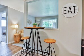 A modern kitchen with a central island, stools, and a 'EAT' sign on the wall. - Jelinek Hideaway Unit 7 - Modern 1BR Apartment (Schofield)