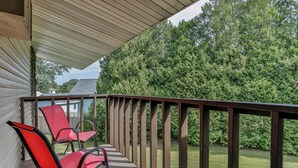 A balcony with two red chairs and a wooden railing.