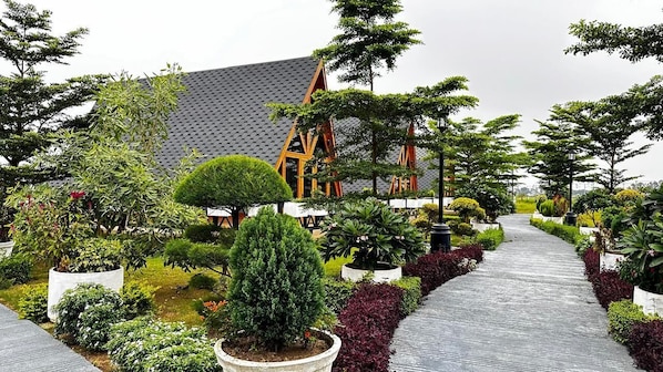A garden pathway leading to a building with a tiled roof and wooden structures.