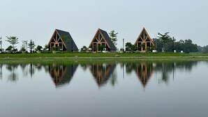 Uma fileira de edifícios modernos com telhados triangulares e um corpo d'água calmo em primeiro plano.