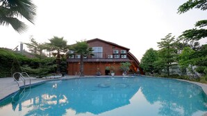 Piscina com uma casa de madeira ao fundo.