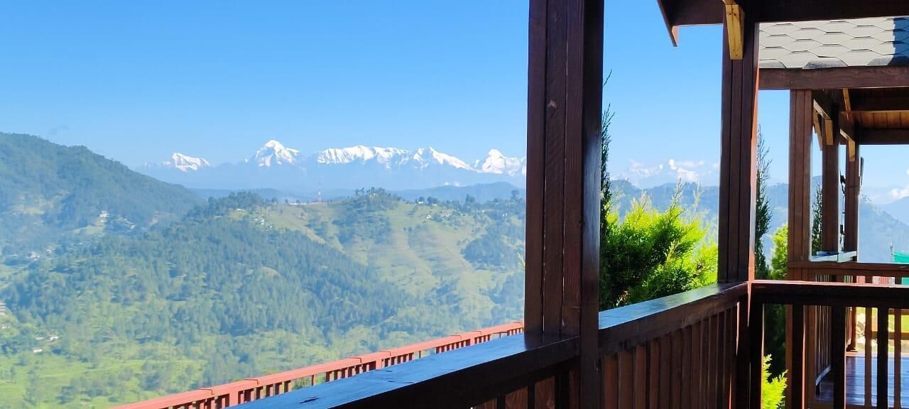 Ein Holzbalkon mit Blick auf schneebedeckte Berge und bewaldete Hügel.