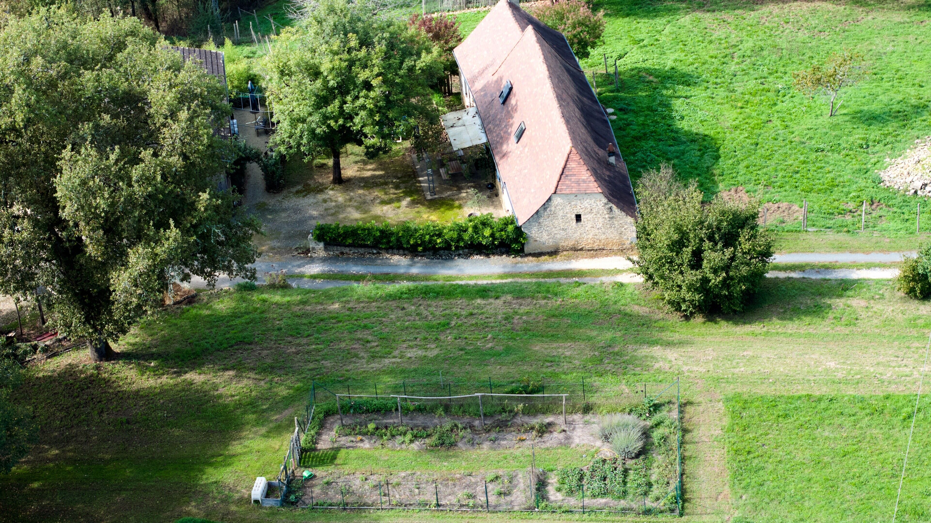 Ein Luftbild einer ländlichen Anlage mit einem Steinhaus, einem eingezäunten Garten und einem kleinen Teich.