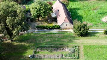 Ein Luftbild einer ländlichen Anlage mit einem Steinhaus, einem eingezäunten Garten und einem kleinen Teich.